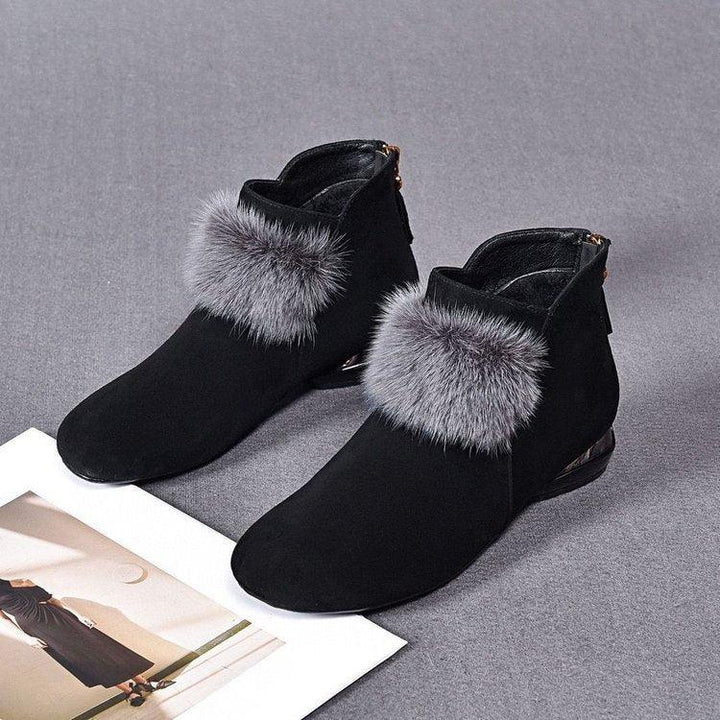 Pair of black suede ankle boots with grey faux fur trim on grey surface