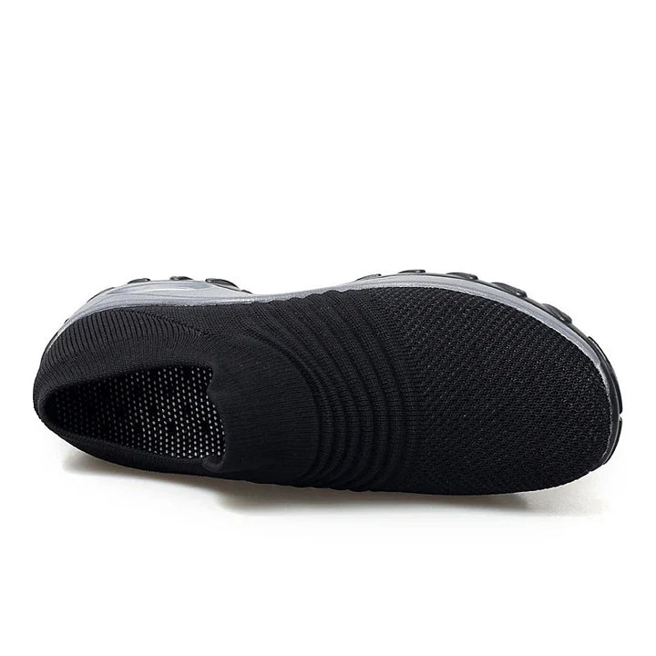 Black slip-on knit sneaker with textured upper and thick rubber sole on white background