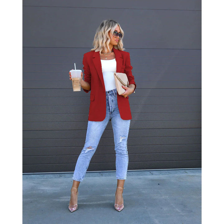 Blonde woman wearing red blazer, white top, ripped jeans, clear heels, holding iced coffee and beige clutch