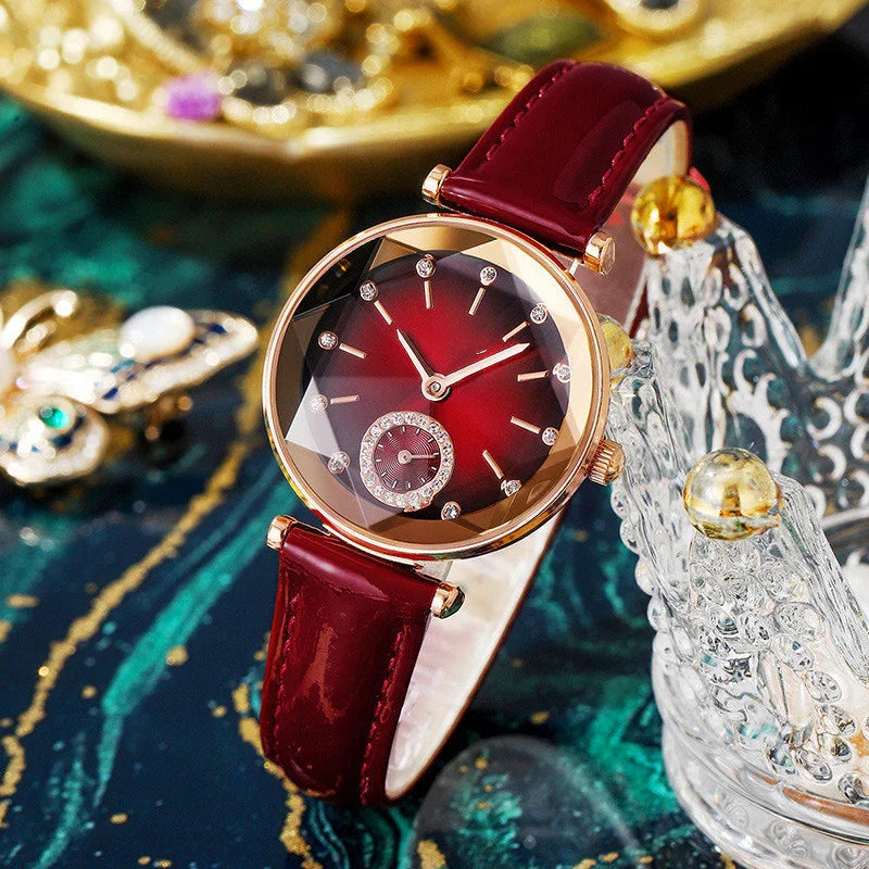Elegant red leather strap watch with gold case and crystal-accented dial on dark decorative surface