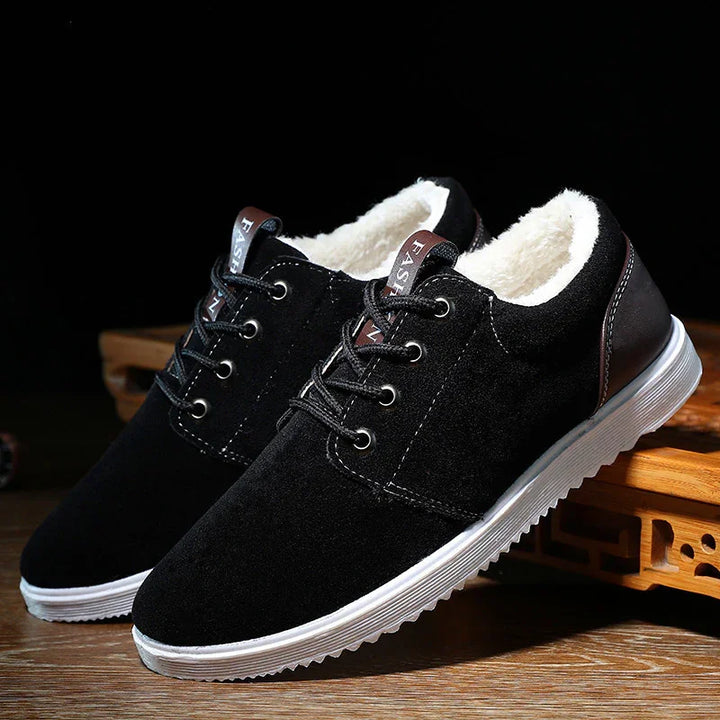 Black winter shoes with white fleece lining, brown heel detail, and white rubber sole on wooden surface
