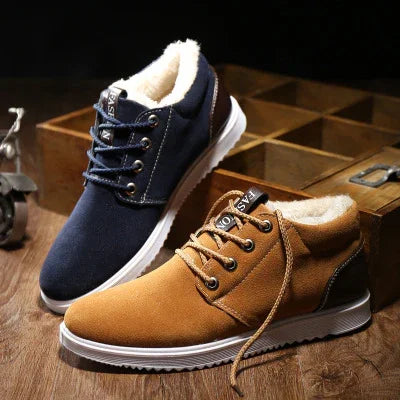 Pair of casual lace-up winter shoes with warm fur lining in navy blue and tan colors on wooden surface