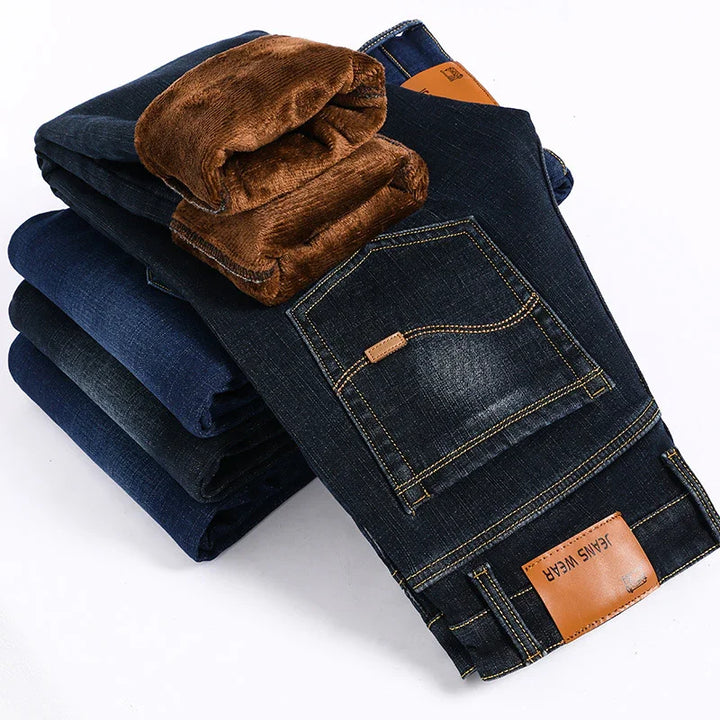 Stack of dark blue denim jeans with visible brown fleece lining and leather label reading Jeans Wear