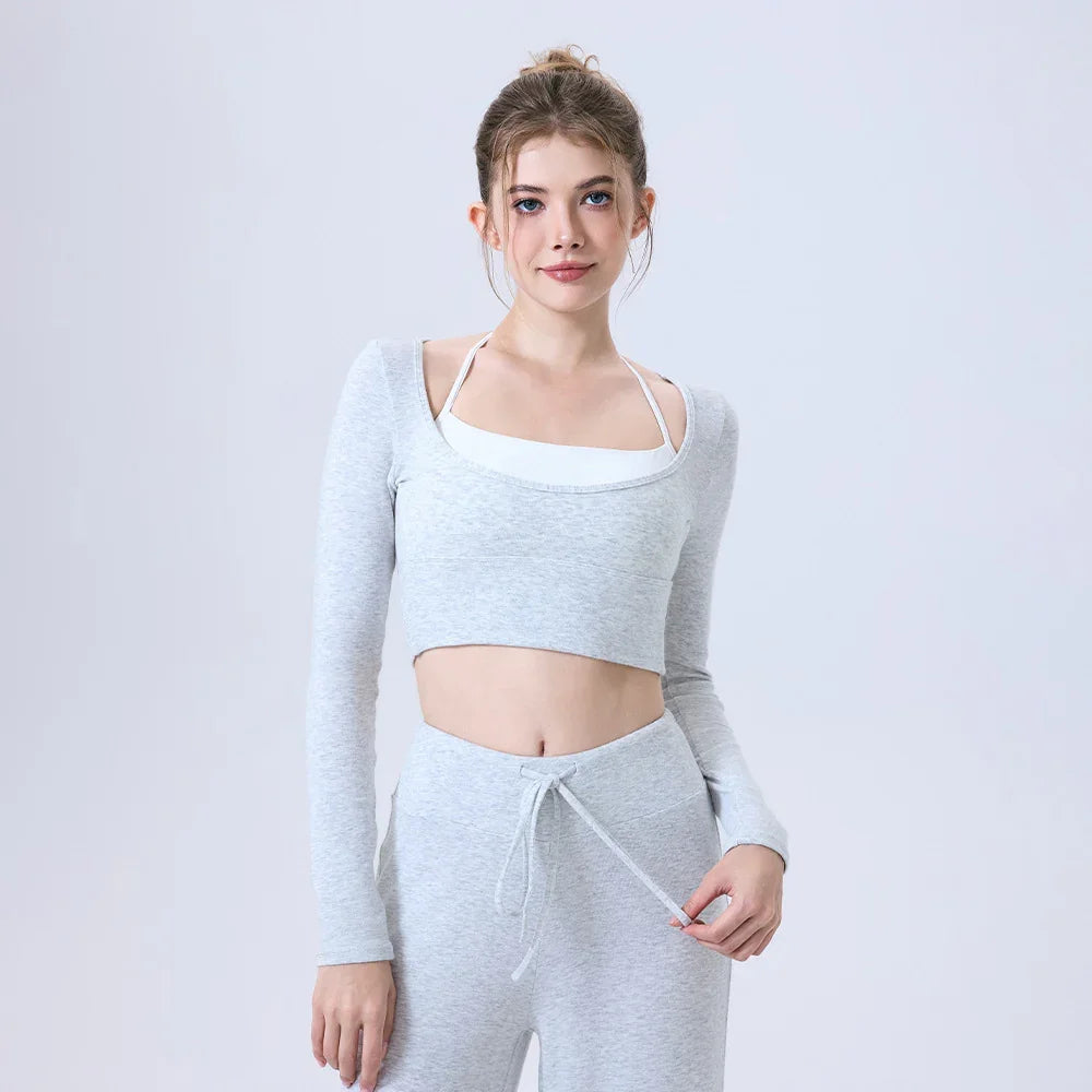 Young woman in gray crop top and pants with drawstring posing against light gray background
