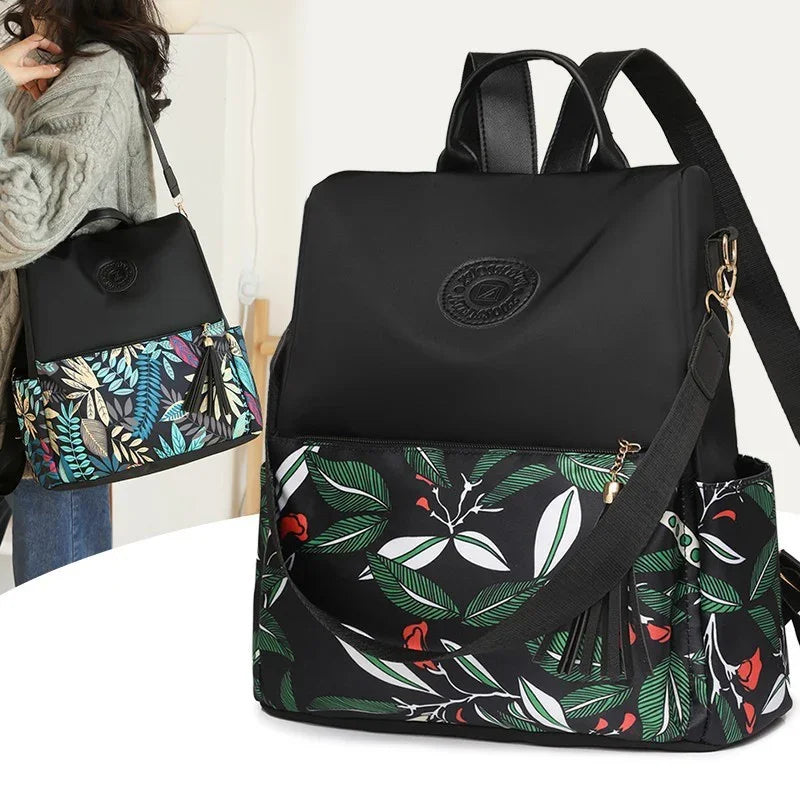 Black fashion backpack with green and white leaf pattern and red floral accents, side pocket and removable strap
