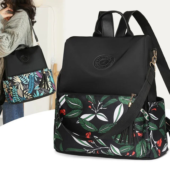 Black fashion backpack with green and white leaf pattern and red floral accents, side pocket and removable strap