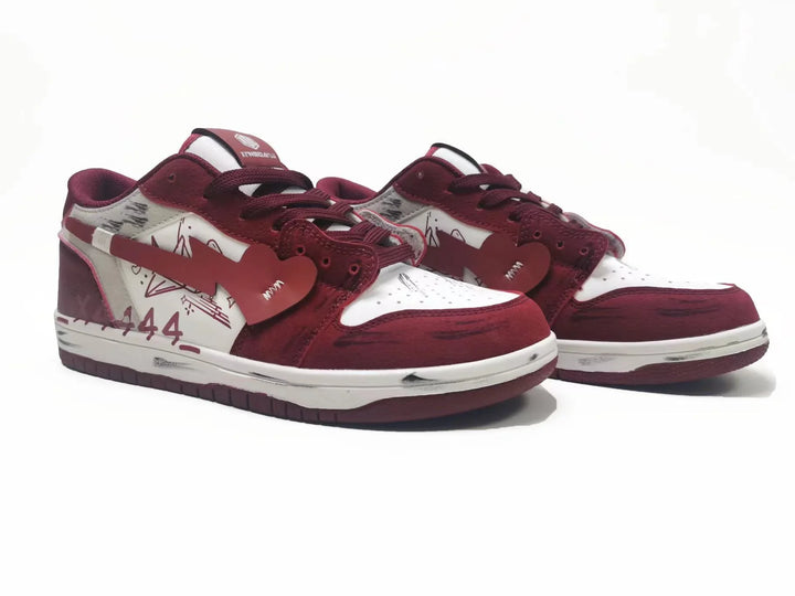 Pair of burgundy and white low-top sneakers with heart-shaped swoosh and graffiti accents