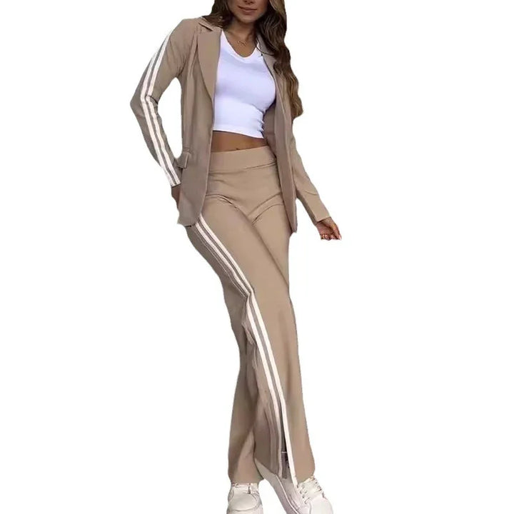 Woman wearing beige sporty pantsuit with white side stripes and white crop top with sneakers