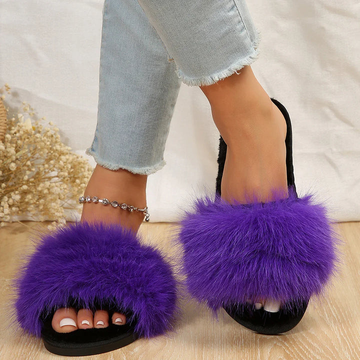 Feet wearing black slides with vibrant purple fluffy fur, paired with light blue frayed jeans