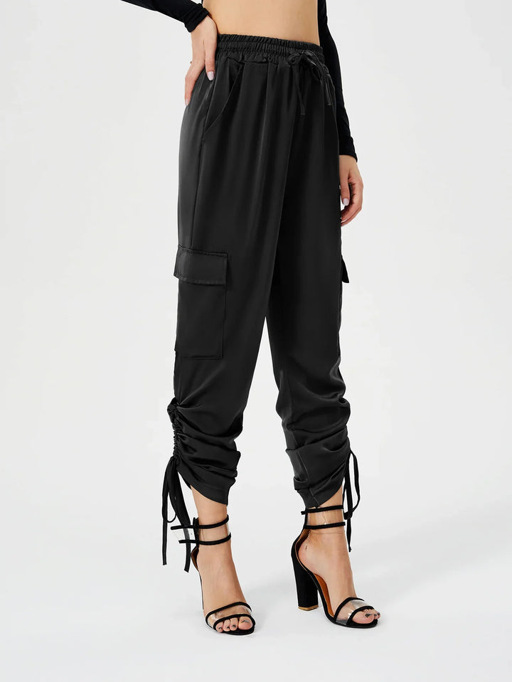 Woman modeling black cargo jogger pants with ruched tie details and high-heeled sandals