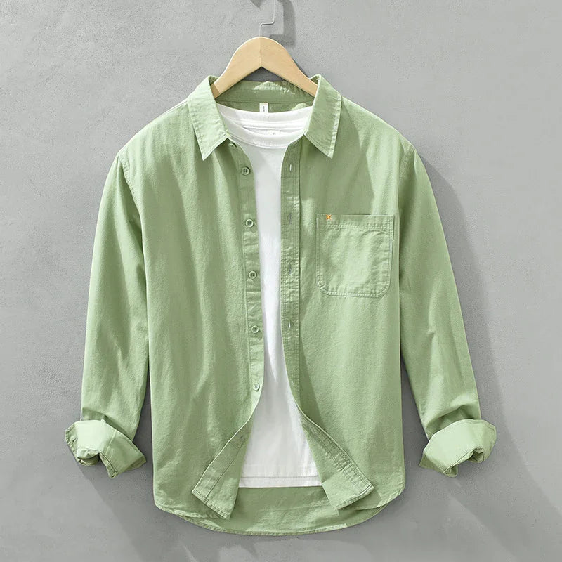 Light green casual button-up shirt with front pocket over a white t-shirt on wooden hanger