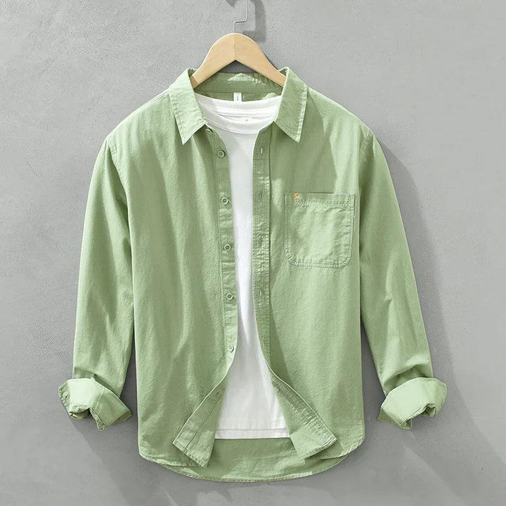 Light green casual button-up shirt with front pocket over a white t-shirt on wooden hanger