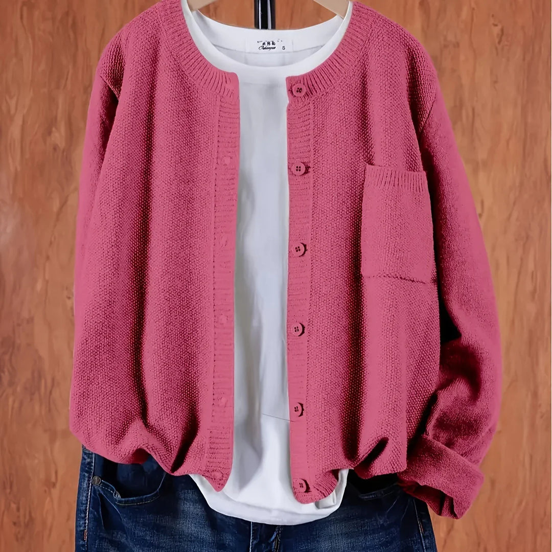 Pink knitted cardigan with buttons over a white T-shirt and blue jeans on wooden background