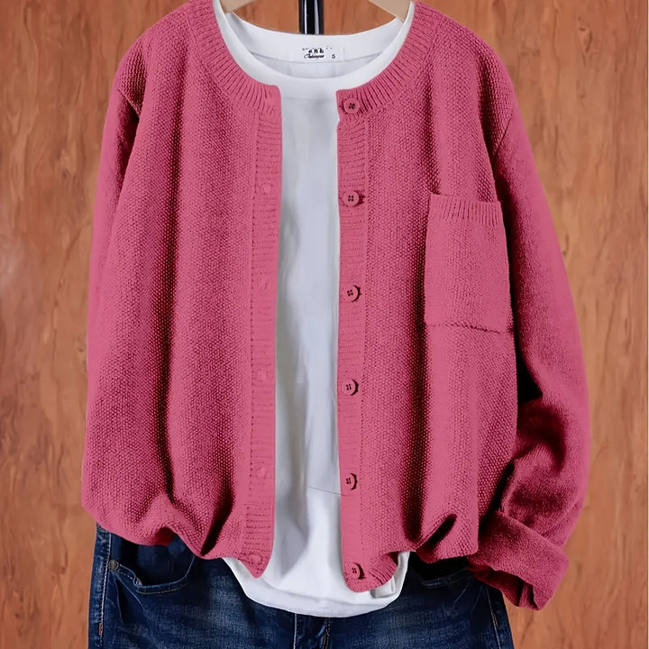 Pink knitted cardigan with buttons over a white T-shirt and blue jeans on wooden background
