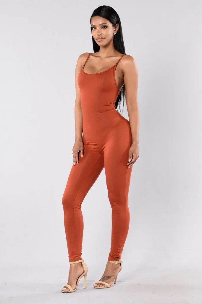 Woman wearing rust orange sleeveless jumpsuit and beige heels on plain background