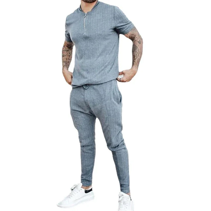 Man wearing gray short sleeve zip-up shirt and matching jogger pants with white sneakers