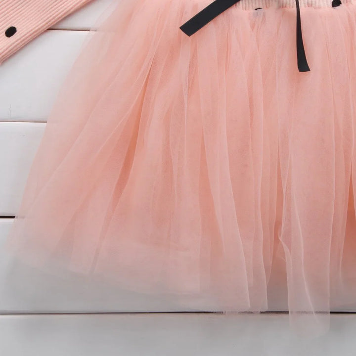 Light pink tulle skirt with black ribbon detail on white wooden background