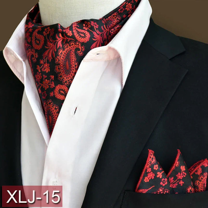 Black suit jacket with white shirt, red and black paisley ascot tie, and matching pocket square