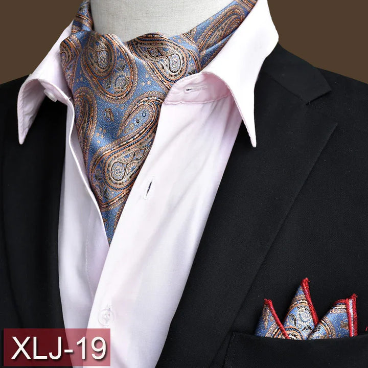 Blue and gold paisley ascot scarf with matching pocket square on black suit and white shirt