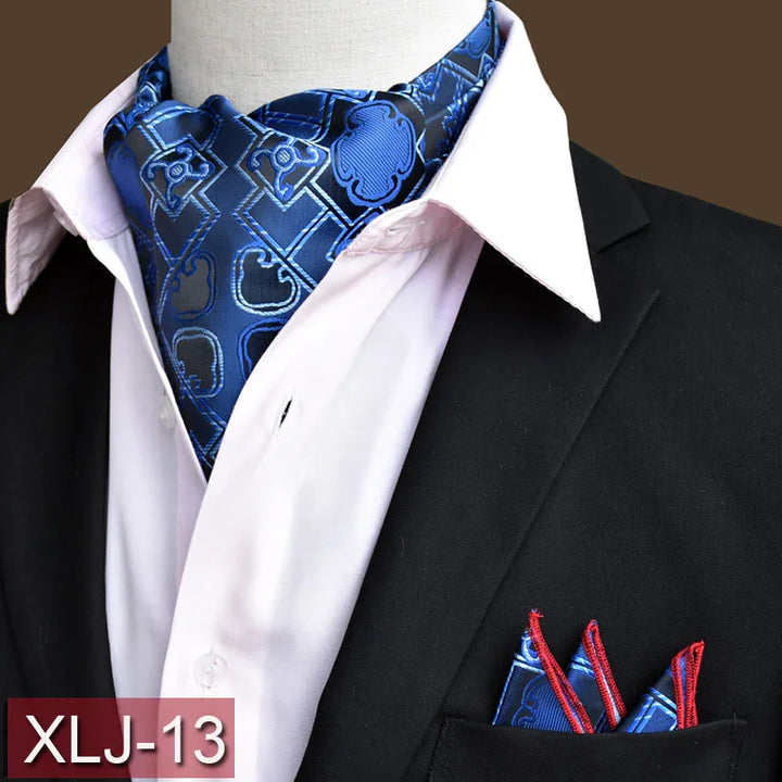 Blue patterned silk ascot paired with matching pocket square, white shirt, and black suit jacket