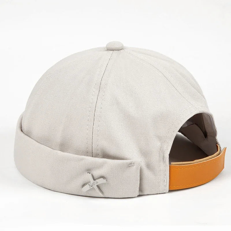 Light beige cotton beanie cap with rolled brim and orange adjustable strap on white background