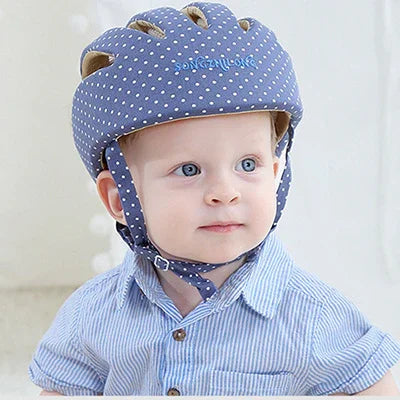 Toddler wearing blue polka dot safety helmet and striped shirt indoors