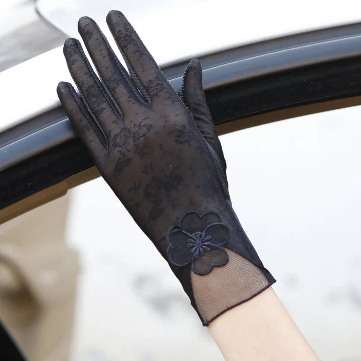 Hand wearing elegant black lace gloves with floral pattern near car window