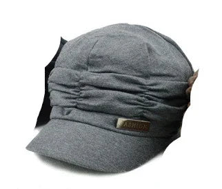 Grey ruched fabric cap with a small leather patch label reading ASHIOU on the brim