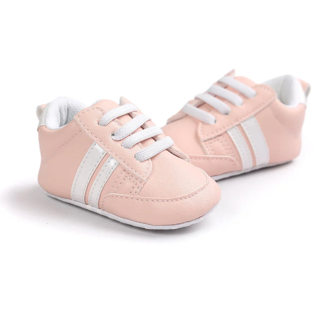 Pair of soft pink baby sneakers with white laces and stripes on white background