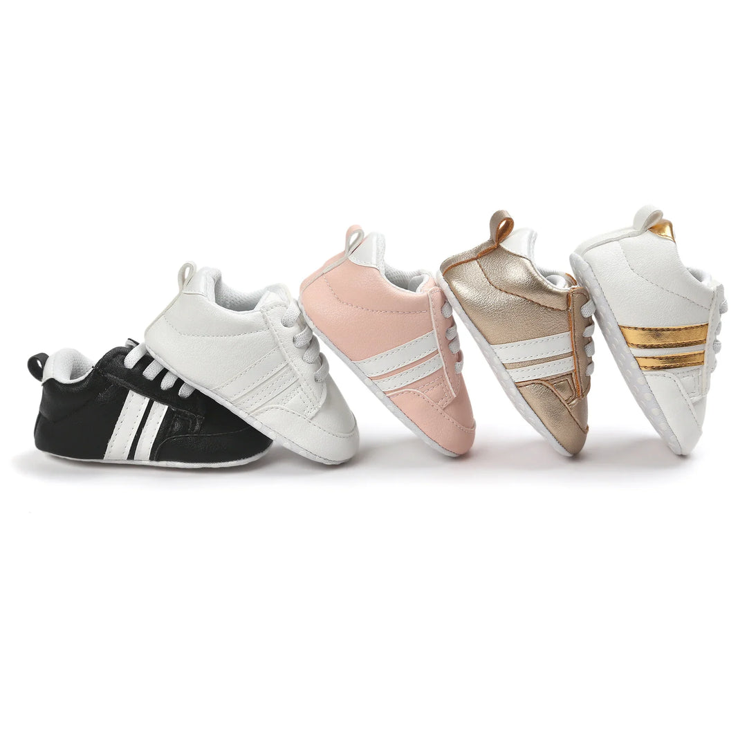 Five pairs of baby soft sole sneakers in black, white, pink, metallic gold, and white with gold stripes