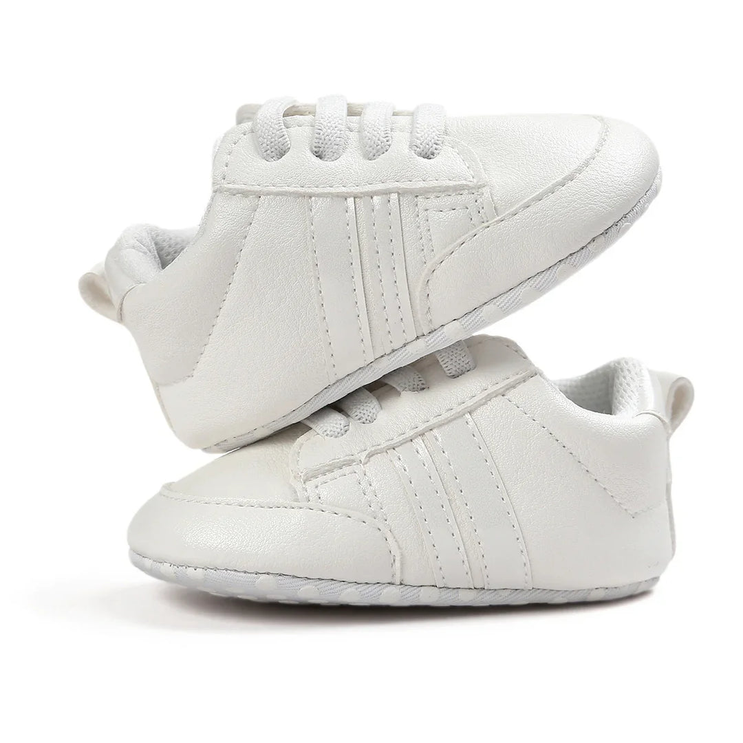 Pair of white baby sneakers with textured soles and laces on white background