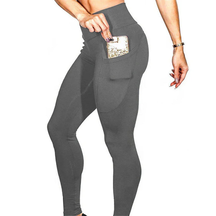 Woman wearing high-waisted gray leggings with side pocket holding a smartphone