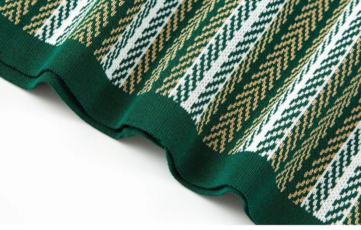 Close-up of green knitted fabric with white and brown herringbone pattern and scalloped edge