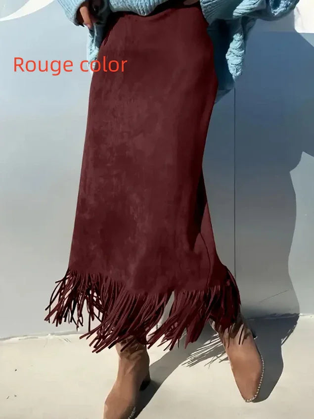 Woman wearing a rouge color fringe midi skirt paired with camel suede ankle boots and a blue knit sweater