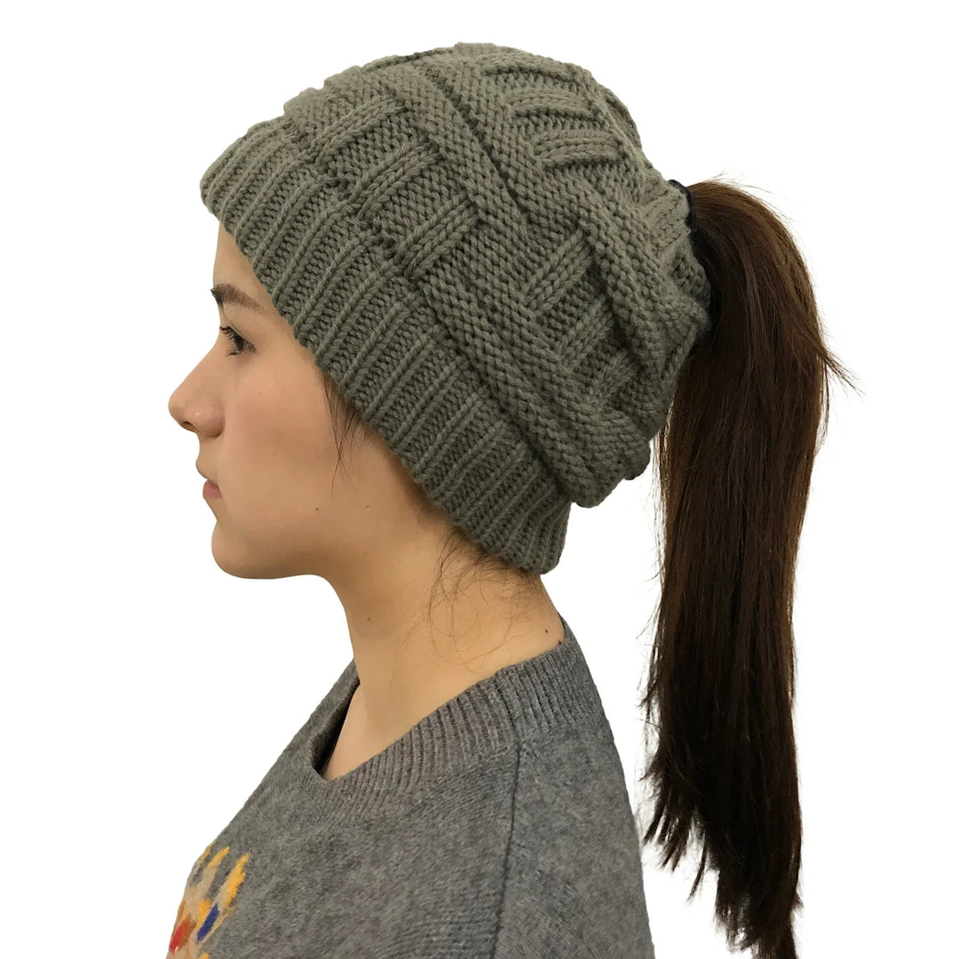 Side view of woman wearing olive green knit ponytail beanie with brown hair in ponytail