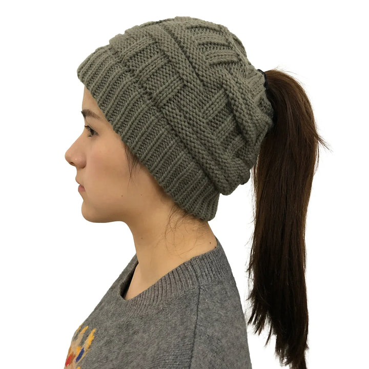Side view of woman wearing olive green knit ponytail beanie with brown hair in ponytail