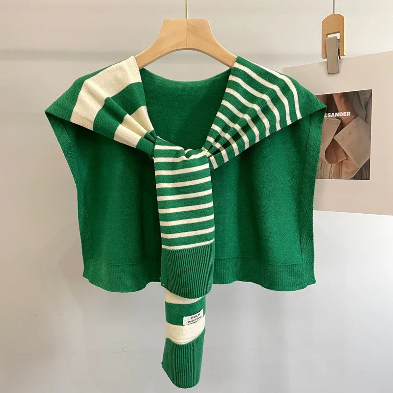 Green knit vest with striped green and white sweater draped over shoulders on wooden hanger