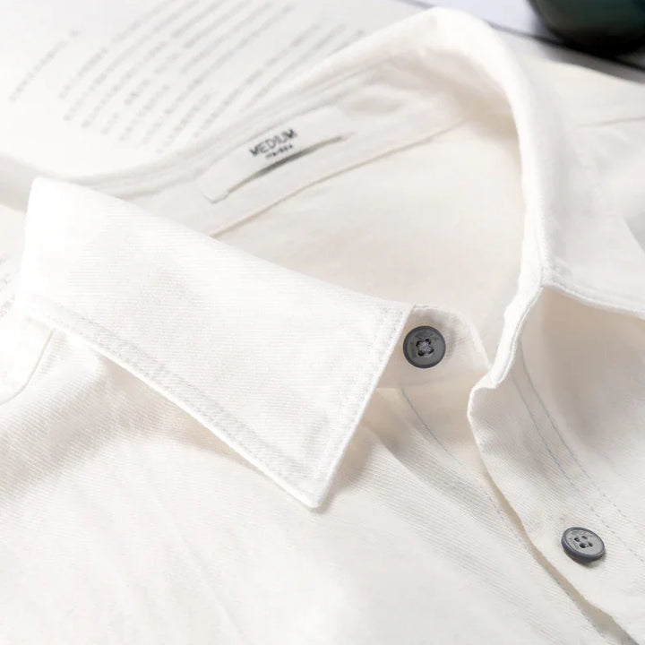 Close-up of a white medium-sized cotton shirt collar with gray buttons on a flat surface