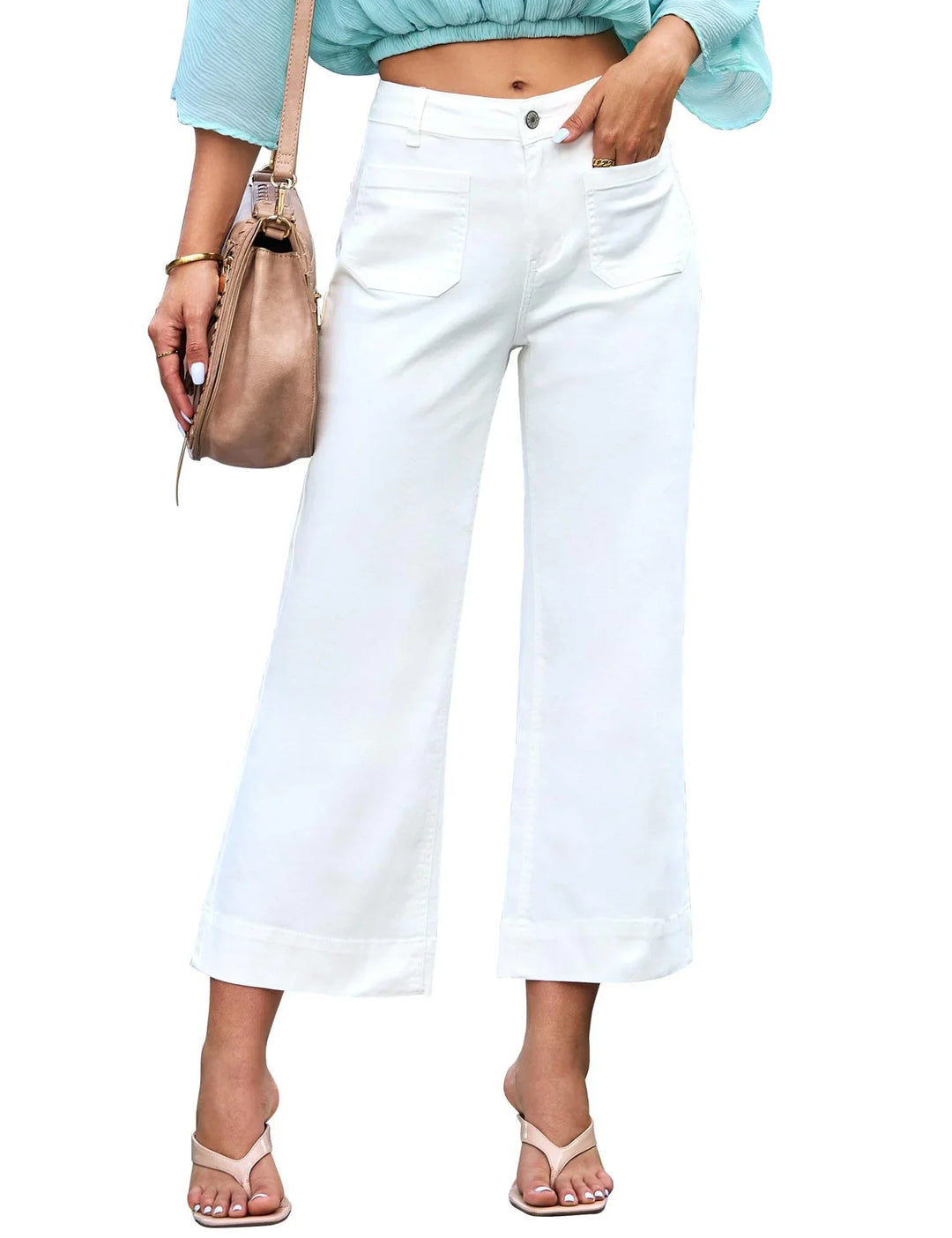 Woman wearing white wide-leg cropped pants with pockets and a light blue top, carrying a beige handbag