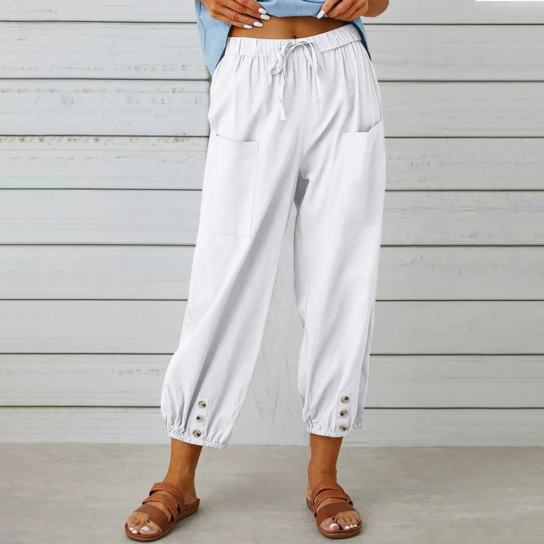 Woman wearing white casual cropped pants with pockets and button details, paired with brown sandals