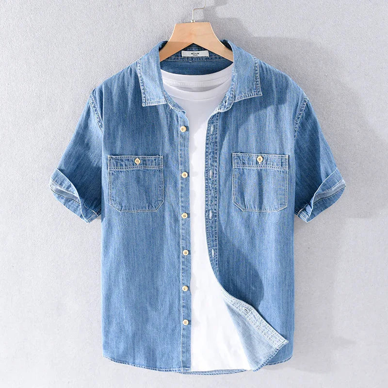 Light blue short-sleeve denim shirt over white t-shirt on wooden hanger against gray background