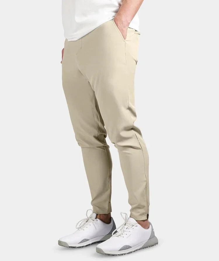 Men's beige slim-fit jogger pants paired with white and gray sneakers against white background