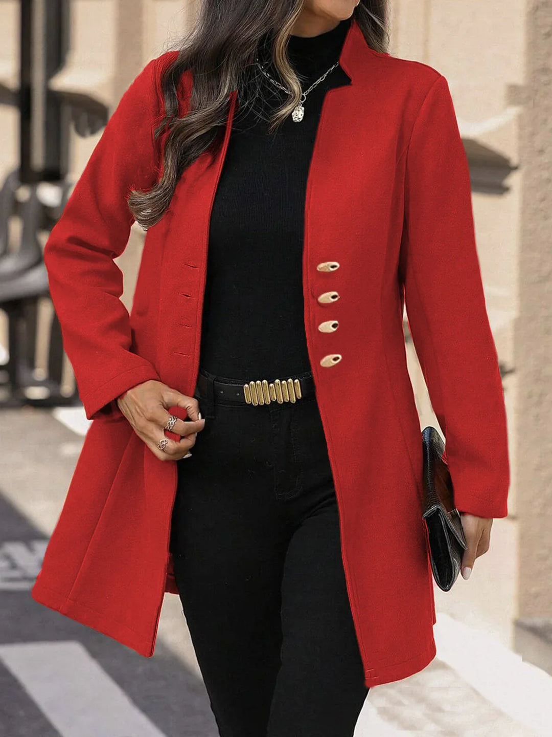 Woman wearing stylish red coat with gold buttons, black turtleneck, black pants, and holding a clutch