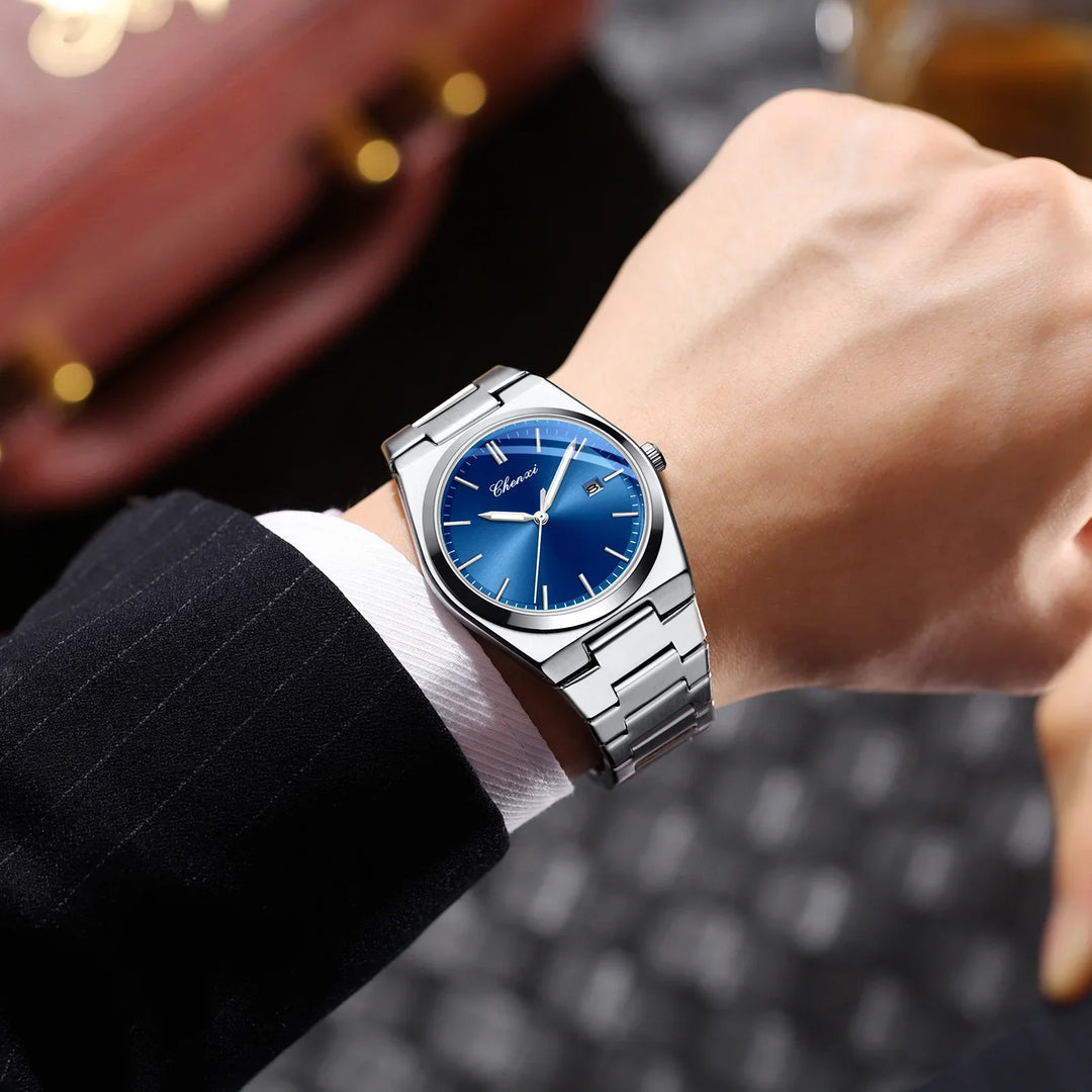 Silver wristwatch with blue dial and date display on male wrist in black suit