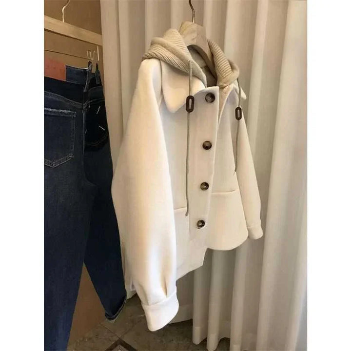 White button-up jacket with ribbed collar hanging next to blue jeans on wooden hangers