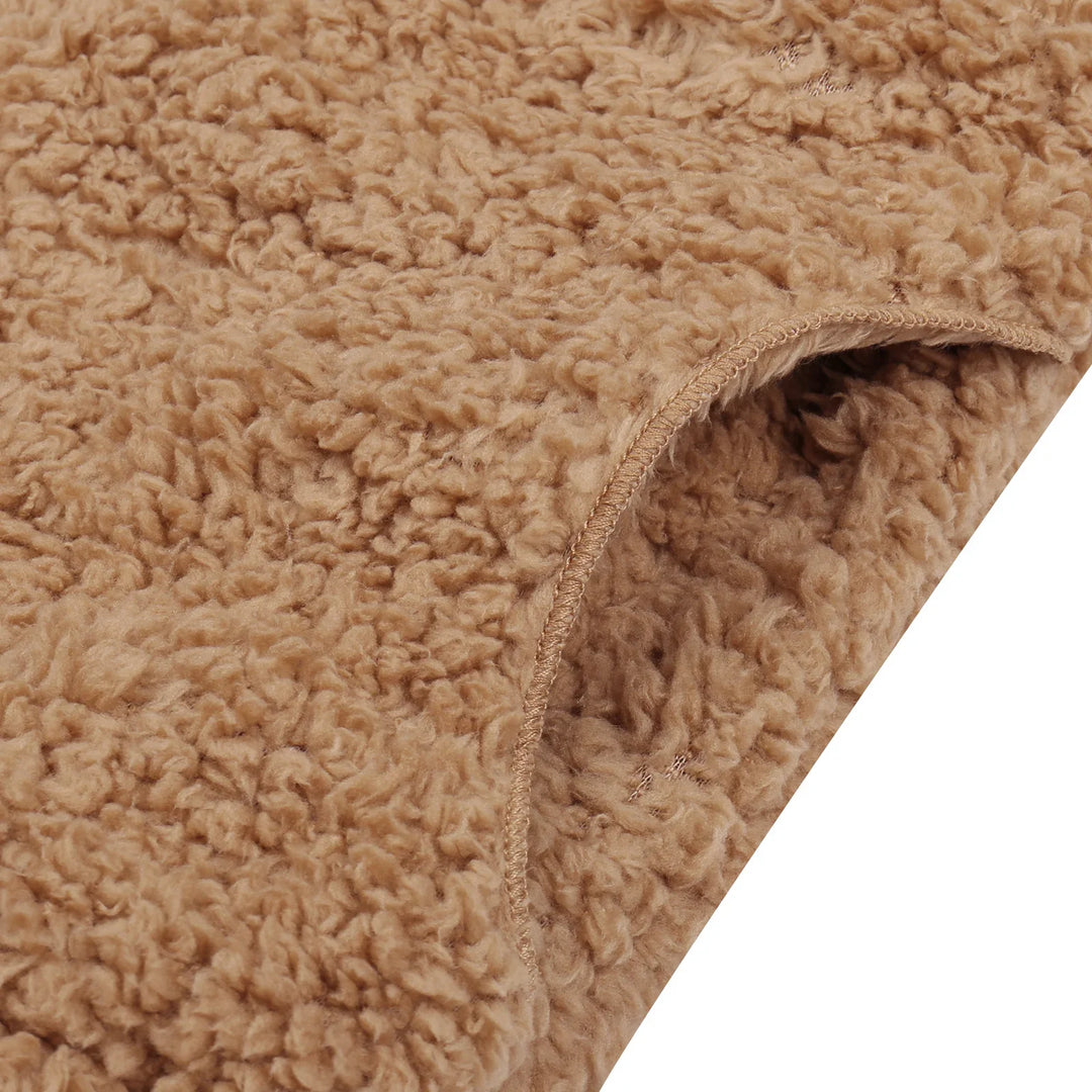 Close-up of brown sherpa fleece fabric with soft, textured plush surface and stitched edge
