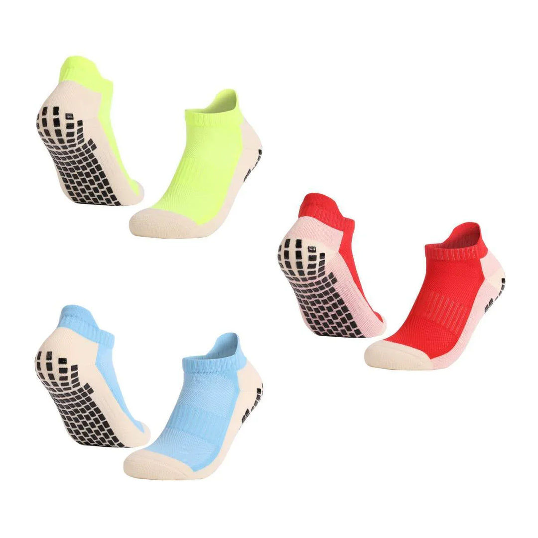 Three pairs of non-slip ankle socks in neon yellow, red, and light blue with black grip soles