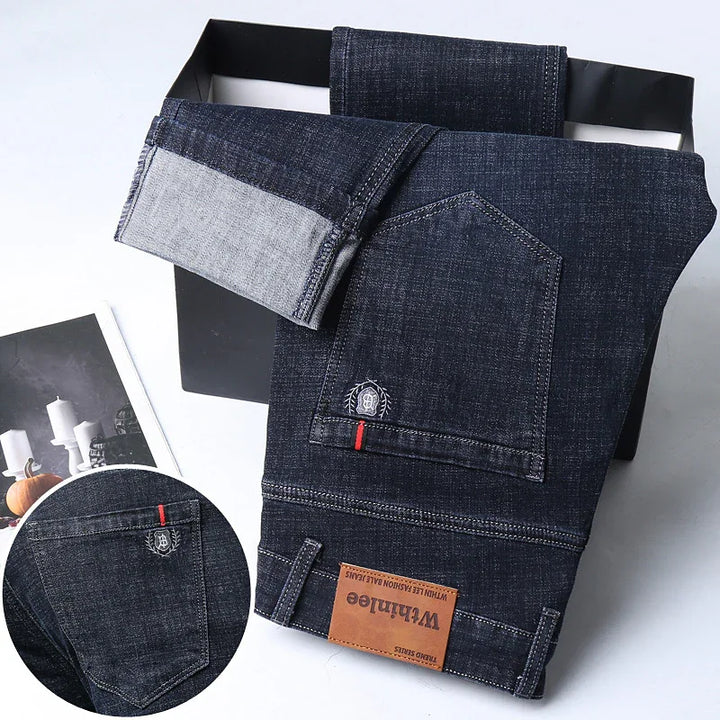 Dark blue denim jeans folded in black box with visible pocket and leather brand label Whthinlee