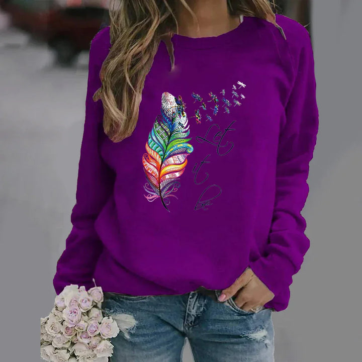 Purple sweatshirt with colorful feather design and 'Let it be' text, worn with distressed jeans