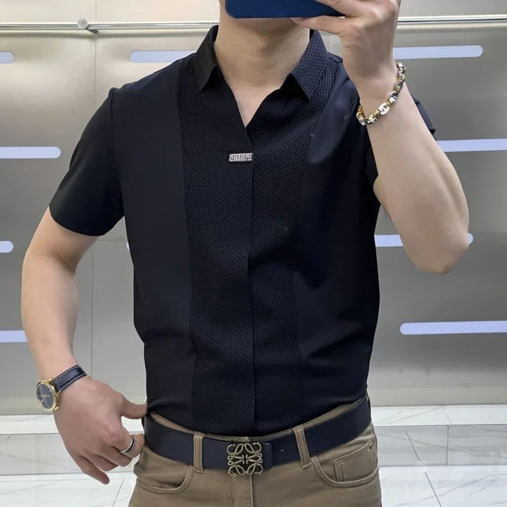 Man wearing black short-sleeve shirt with textured front panel and tan pants with black belt